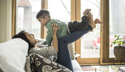 Mother playing with young son (2 yrs) on couch at home